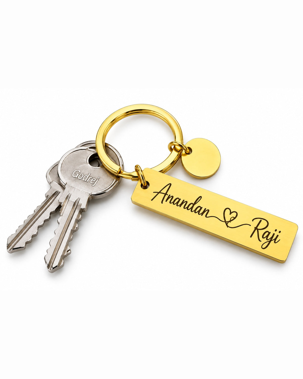 Gold steel couple keychain with engraved names Anandan and Raji, heart, key ring and round charm on a white background